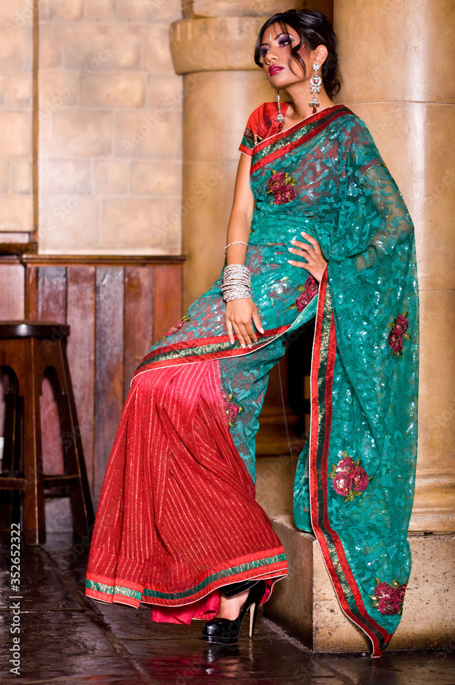 Indoor portrait of pretty traditional Indian Bengali woman model wearing sari, jewellery and makeup