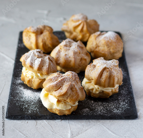 Canvas-taulu Cream puffs or profiteroles dusted with sugar powder and and filled with whipped