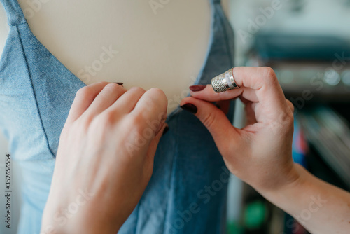 Young woman fashion designer measuring mannequin, seamstress holding tape working with dummy in cozy home or tailor shop, dressmaking and sewing concept