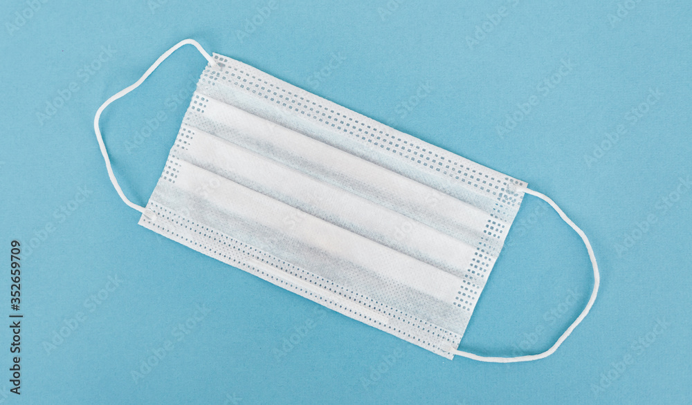 Surgical mask with rubber ear straps. Typical 3-ply surgical mask to cover the mouth and nose. Procedure mask from bacteria. Protection concept. Surgical mask with rubber ear straps. Typical 3-ply surgical mask to cover the mouth and nose. Procedure mask from bacteria. Protection concept.