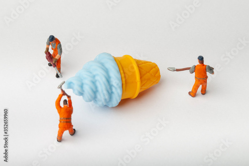 Miniature people move ice cream, cooking and decoration concept. The concept of a collective solution to any problem. Close-up view.