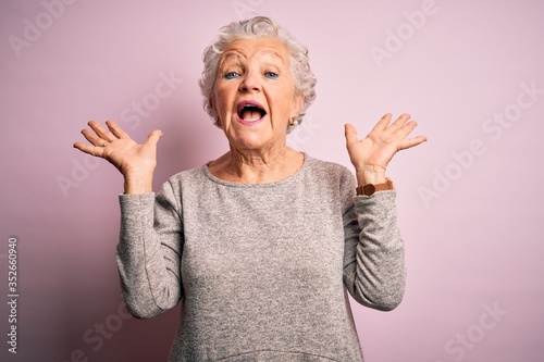Vászonkép Senior beautiful woman wearing casual t-shirt standing over isolated pink background celebrating crazy and amazed for success with arms raised and open eyes screaming excited