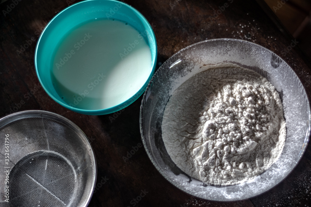 Flour, milk and sieve on a wood table Flour, milk and sieve on a wood table