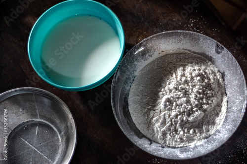 Flour, milk and sieve on a wood table