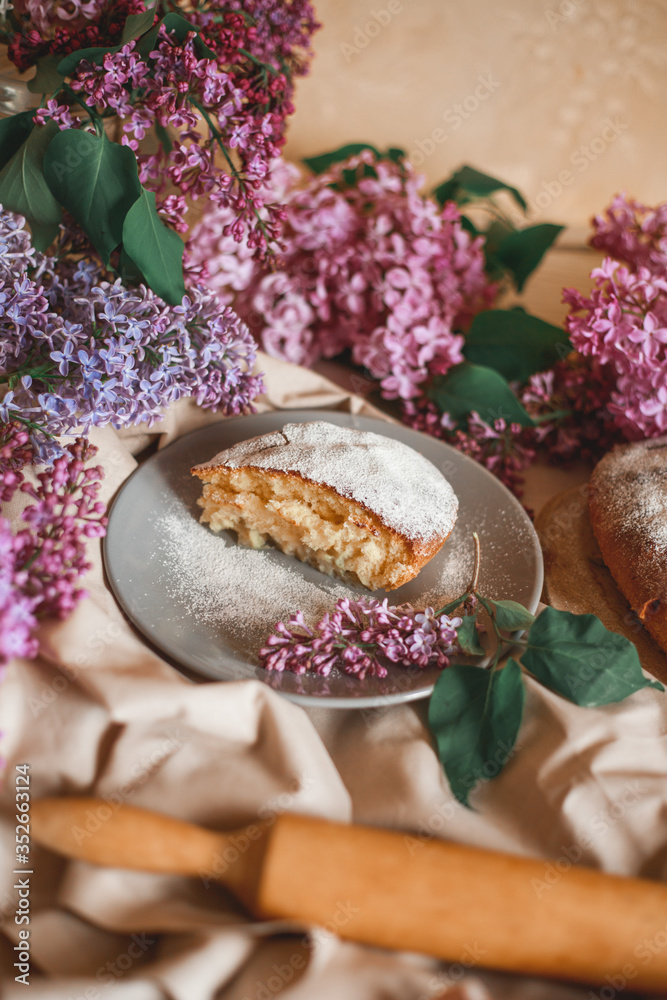 Homemade Apple pie on a wooden table next to a bowl of lilacs. Gentle toning. Homemade Apple pie on a wooden table next to a bowl of lilacs. Gentle toning.
