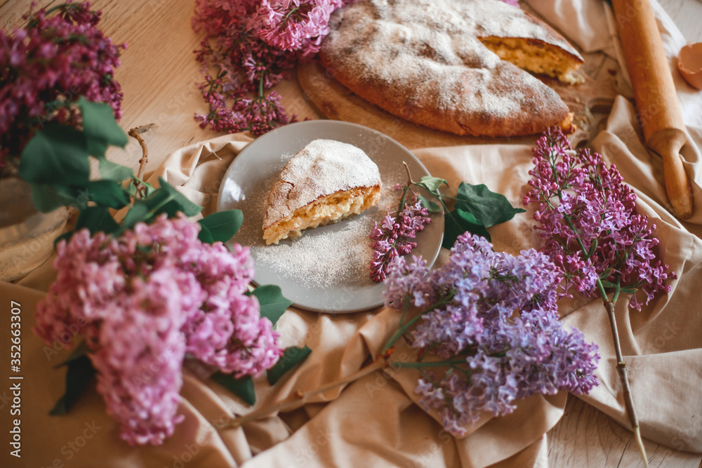 Homemade Apple pie on a wooden table next to a bowl of lilacs. Gentle toning. Homemade Apple pie on a wooden table next to a bowl of lilacs. Gentle toning.