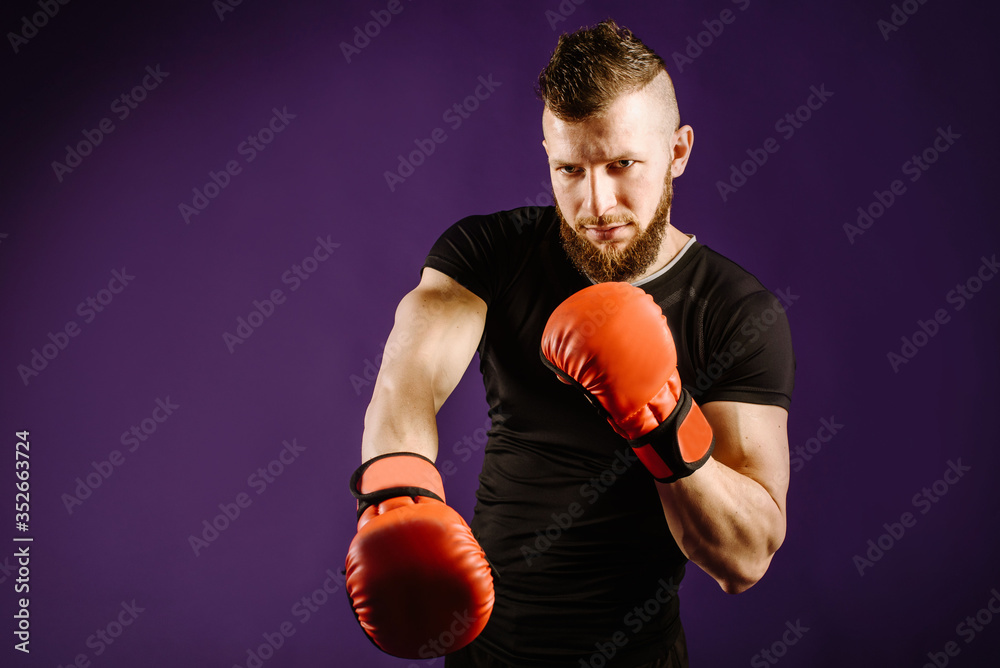 Young muscular man wearing boxing gloves in studio background