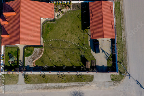 Aerial top view of a private house with paved yard with green grass lawn with concrete foundation floor
