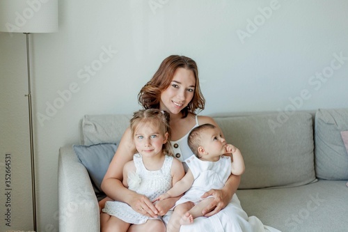 Young beautiful mother Holds her little daughters in her arms. Home comfort. Mothers Day.