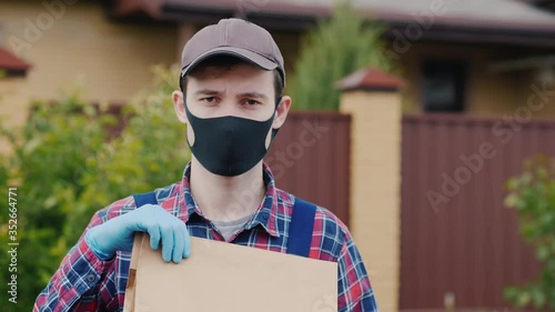 Portrait of a courier with a bag of groceries, stands on the street in the suburbs photo