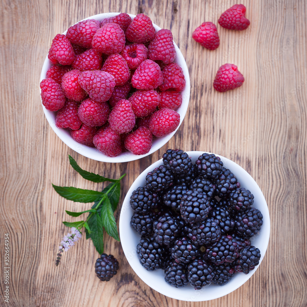 Bowls overflowing with summer berries like raspberries and blackberries. Bowls overflowing with summer berries like raspberries and blackberries.