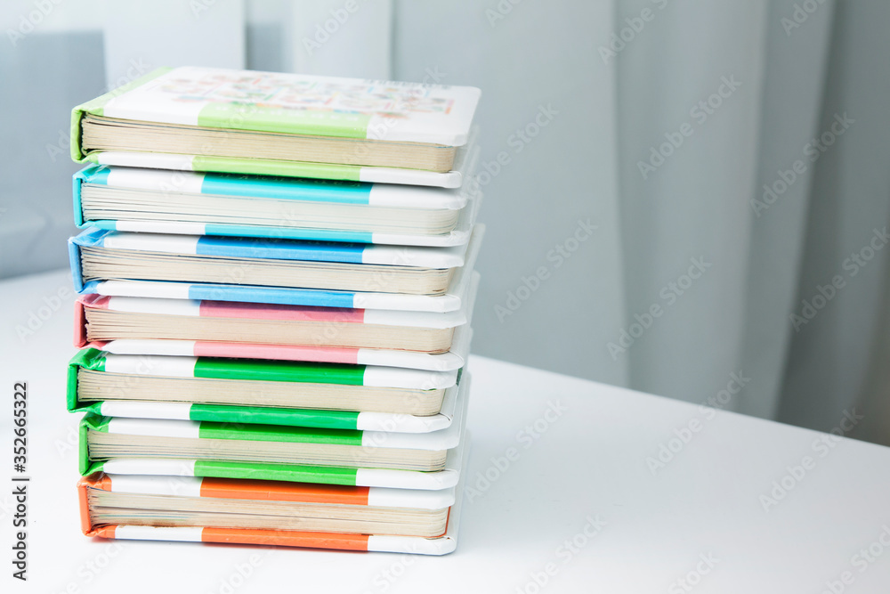 Children's books are stacked on a table in a room. Child development with books concept Children's books are stacked on a table in a room. Child development with books concept