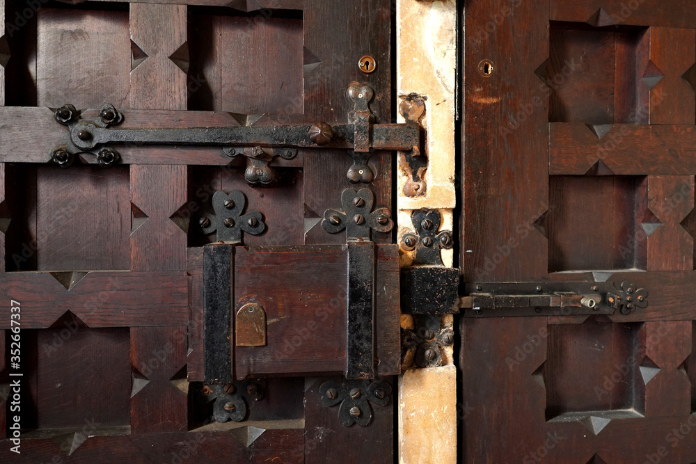 A close-up of a rustic lock and hinges on a church door in the UK