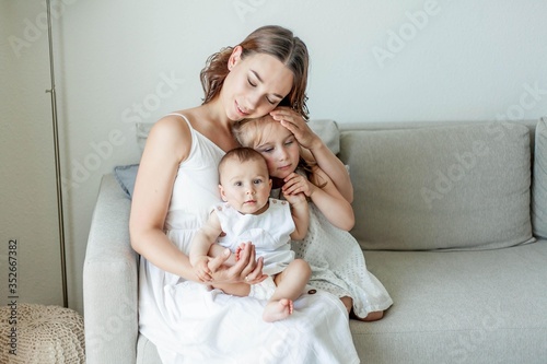 Young beautiful mother Holds her little daughters in her arms. Home comfort. Mothers Day.