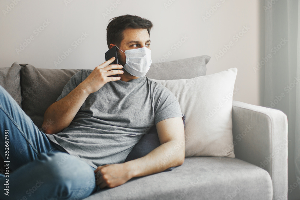 Young man with medical mask working home online at quarantine