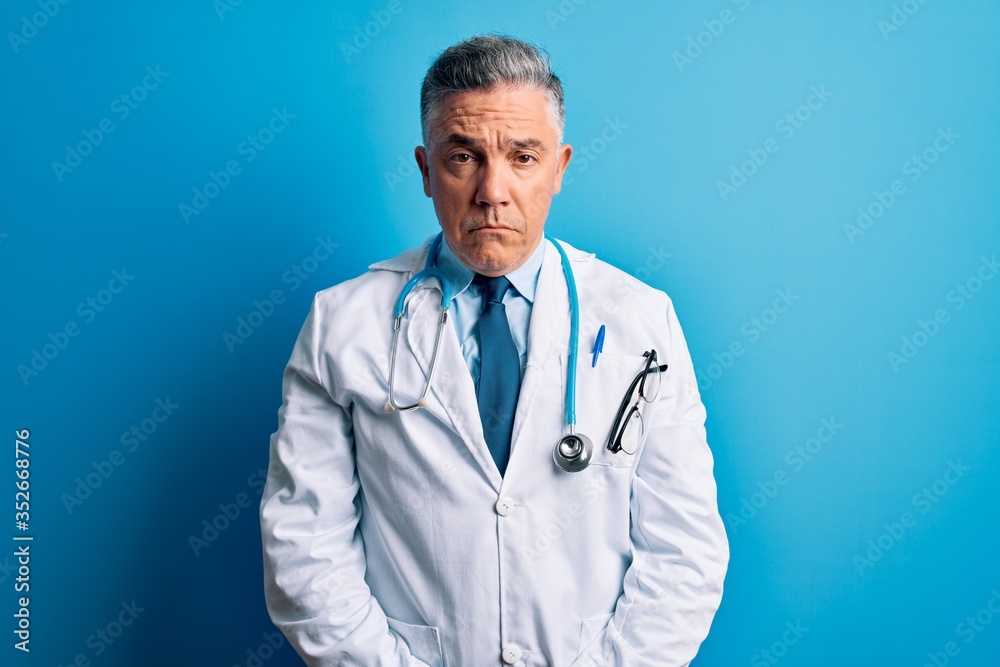 Middle age handsome grey-haired doctor man wearing coat and blue stethoscope depressed and worry for distress, crying angry and afraid. Sad expression. Middle age handsome grey-haired doctor man wearing coat and blue stethoscope depressed and worry for distress, crying angry and afraid. Sad expression.