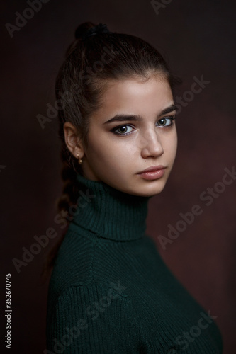 a girl in a green sweater and skirt on a dark background