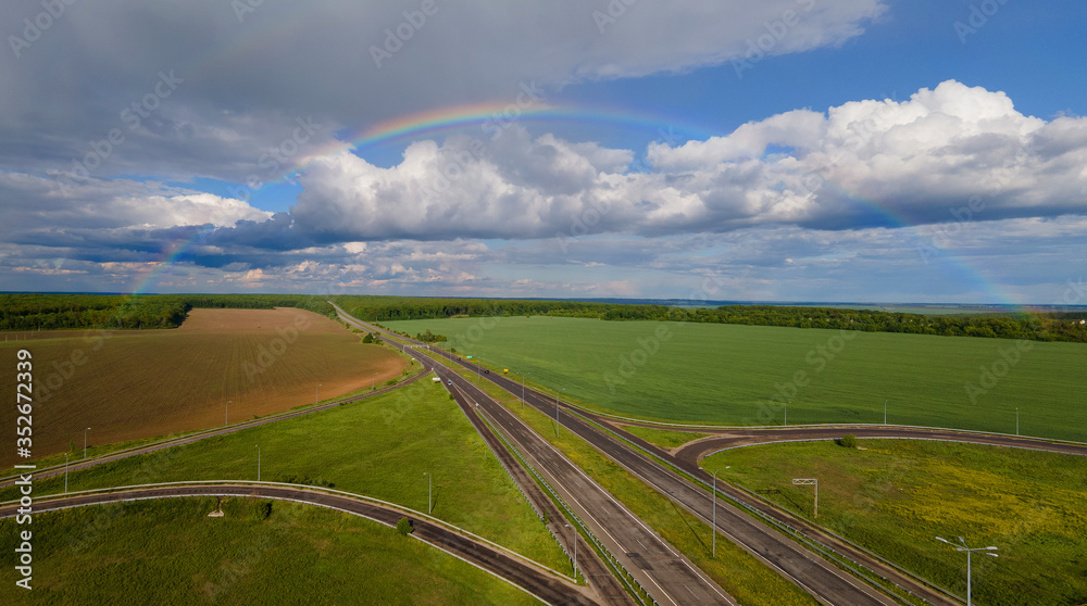 Full rainbow over the highway in green fields