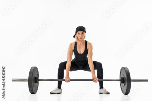 Young woman doing deadlift with a barbell isolated on white. Front view
