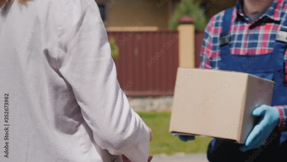 Courier brings parcel to the recipient's house, woman picks it up Courier brings parcel to the recipient's house, woman picks it up