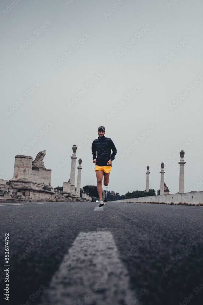 Athletic young man running lonely on a city bridge during a cloudy day