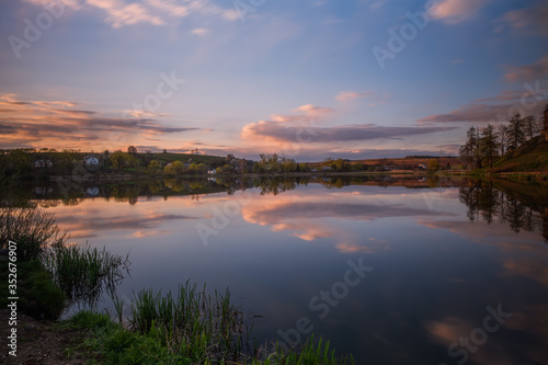 Amazing sunset view of scenic lake near medieval castle on the bank with reflection in the water and reeds on foreground. Svirzh, Ukraine. April 2020