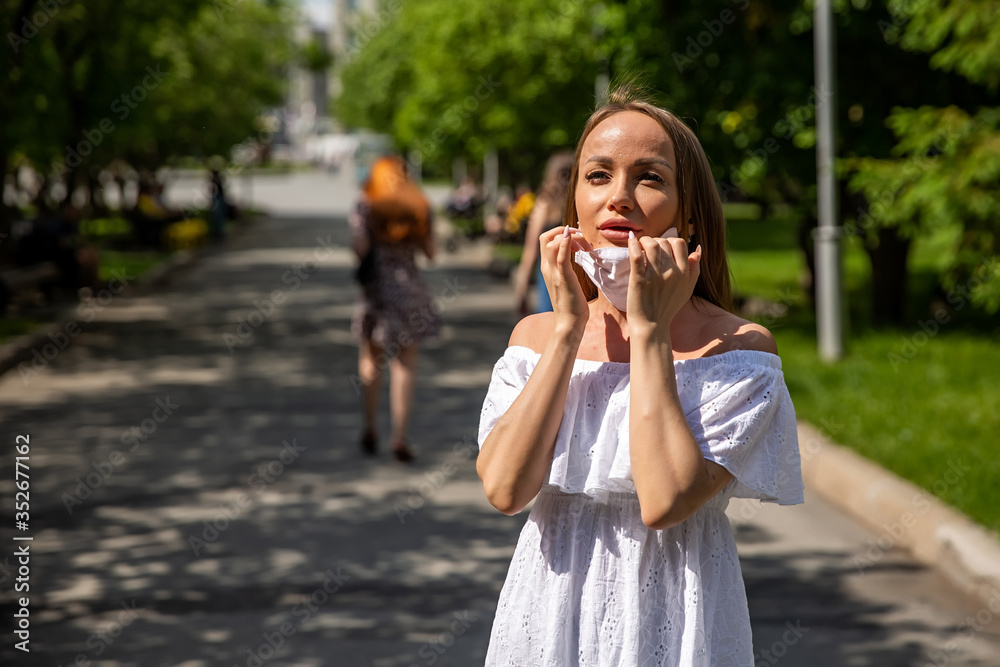 Fototapeta premium girl in the park takes off a medical mask