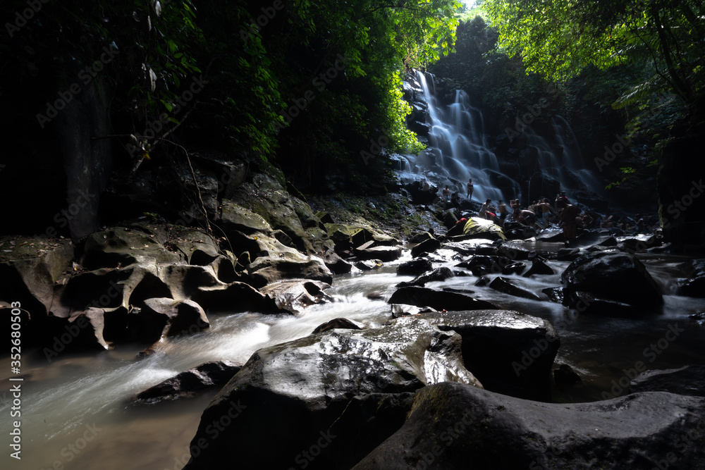 Obraz premium sun shines through the jungle at waterfall in bali indonesia