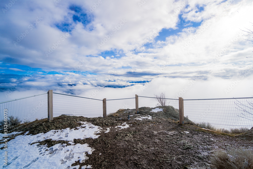 Clouds roll in at the top of the mountain summit with beautiful blue sky's right behind them on Giant head Mountain in Summerland BC