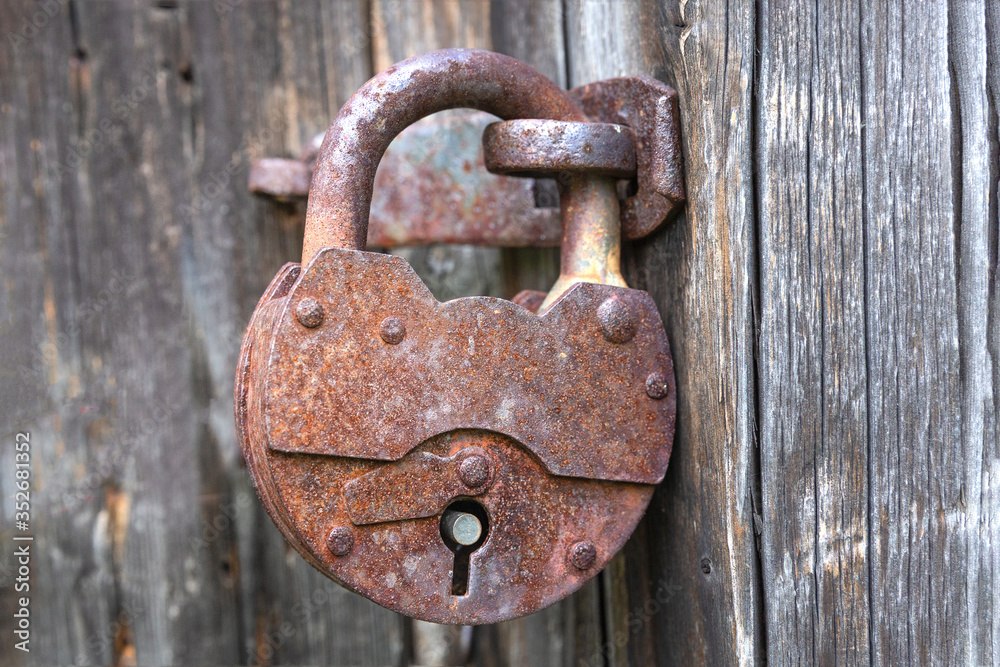 Old iron brown lock on a wooden gray rustic door.Close up.Selective focus.Concept of decoration,vintage design. Old iron brown lock on a wooden gray rustic door.Close up.Selective focus.Concept of decoration,vintage design.