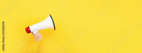 megaphone in hand on a yellow background, attention concept announcement, panoramic mock-up photo