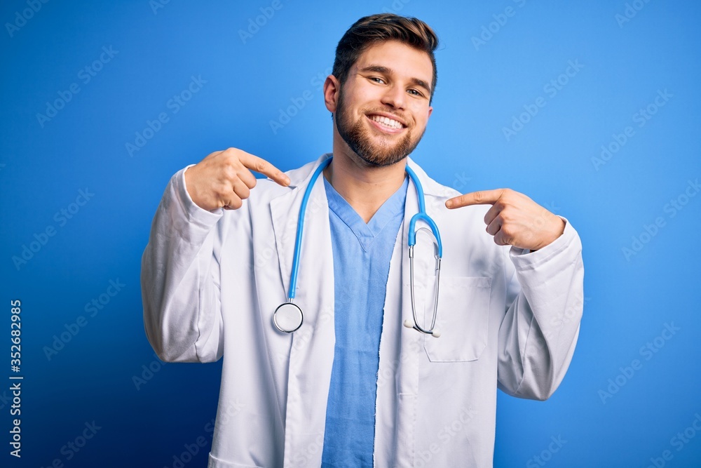 Young blond doctor man with beard and blue eyes wearing white coat and stethoscope looking confident with smile on face, pointing oneself with fingers proud and happy. Young blond doctor man with beard and blue eyes wearing white coat and stethoscope looking confident with smile on face, pointing oneself with fingers proud and happy.