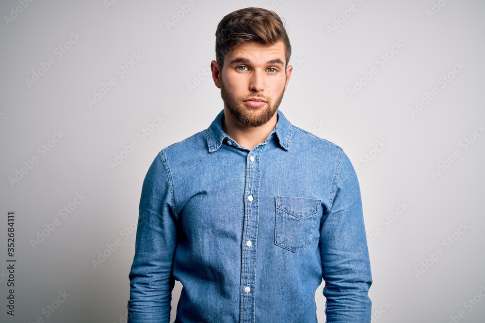 Young handsome blond man with beard and blue eyes wearing casual denim shirt Relaxed with serious expression on face. Simple and natural looking at the camera. Young handsome blond man with beard and blue eyes wearing casual denim shirt Relaxed with serious expression on face. Simple and natural looking at the camera.