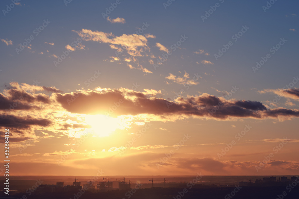 Beautiful sun during an orange sunset on the background of clouds