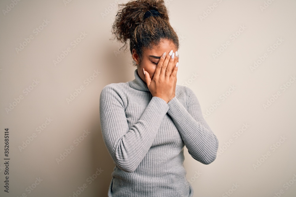 Beautiful african american girl wearing turtleneck sweater standing over white background with sad expression covering face with hands while crying. Depression concept. Beautiful african american girl wearing turtleneck sweater standing over white background with sad expression covering face with hands while crying. Depression concept.