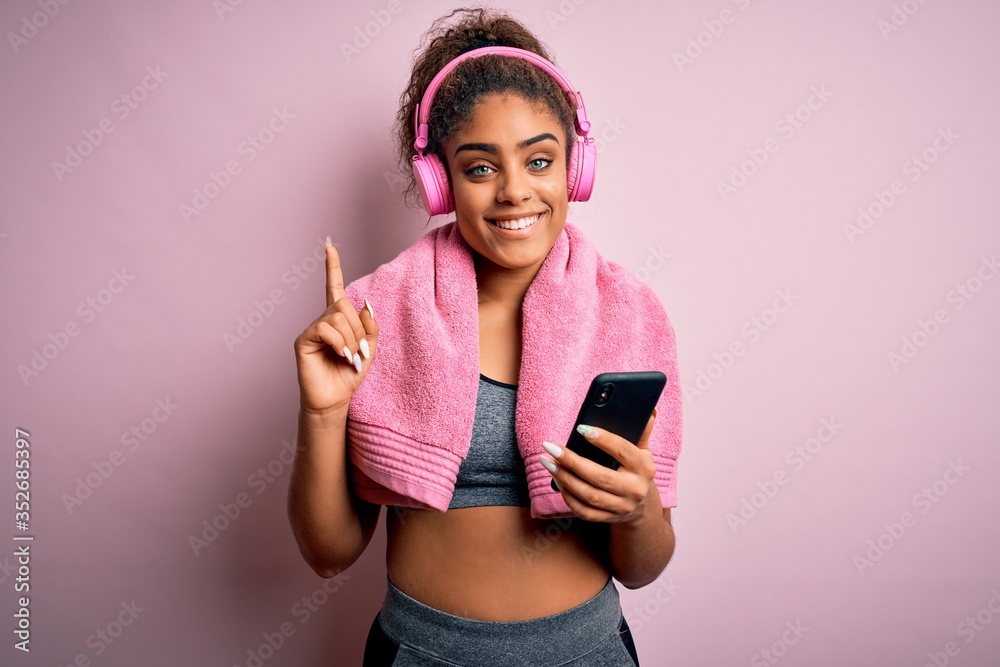 Young african american sportswoman playing tennis using racket over isolated pink background surprised with an idea or question pointing finger with happy face, number one
