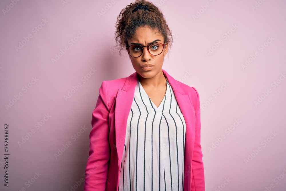 Beautiful african american businesswoman wearing jacket and glasses over pink background skeptic and nervous, frowning upset because of problem. Negative person.