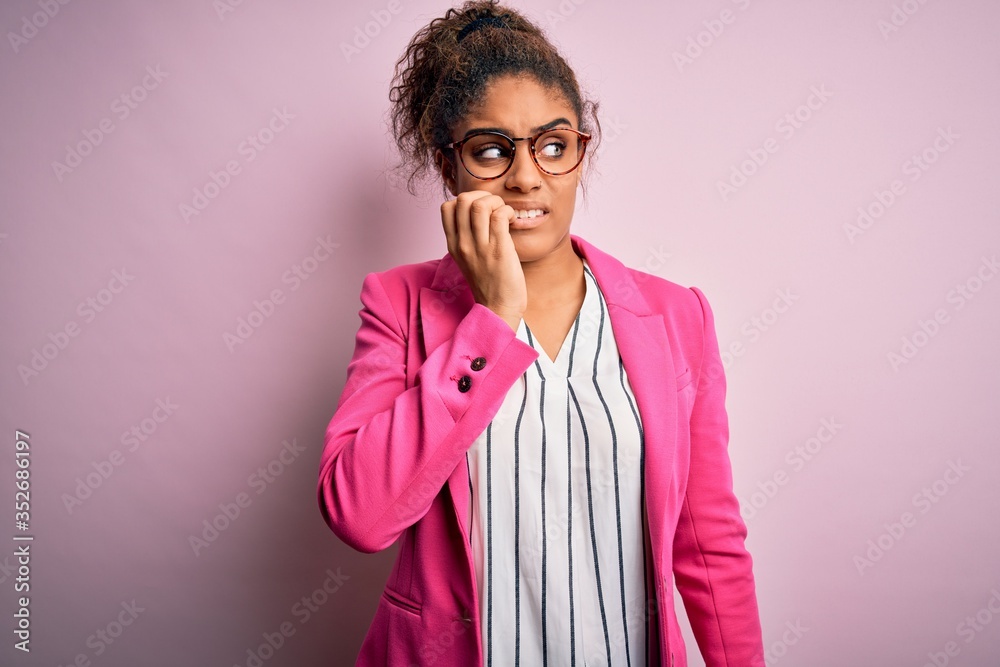 Beautiful african american businesswoman wearing jacket and glasses over pink background looking stressed and nervous with hands on mouth biting nails. Anxiety problem. Beautiful african american businesswoman wearing jacket and glasses over pink background looking stressed and nervous with hands on mouth biting nails. Anxiety problem.