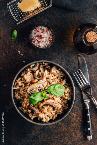 Original italian risotto with mushrooms and parmesan cheese in a dark bowl on a dark background.