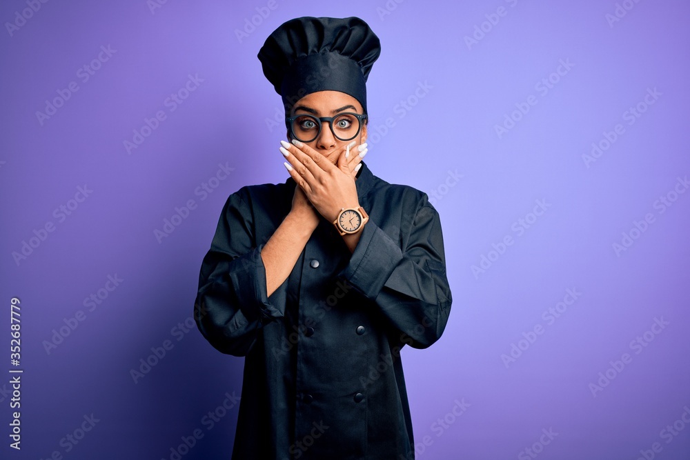 Young african american chef girl wearing cooker uniform and hat over purple background shocked covering mouth with hands for mistake. Secret concept. Young african american chef girl wearing cooker uniform and hat over purple background shocked covering mouth with hands for mistake. Secret concept.