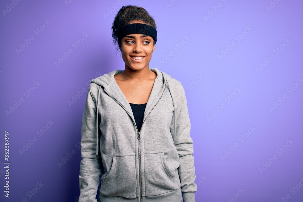 Young african american sportswoman doing sport wearing sportswear over purple background smiling looking to the side and staring away thinking. Young african american sportswoman doing sport wearing sportswear over purple background smiling looking to the side and staring away thinking.