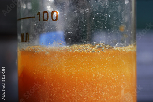 The process of separation of water-insoluble particles of iron oxalate in a beaker. The color of the colloidal solution is orange.