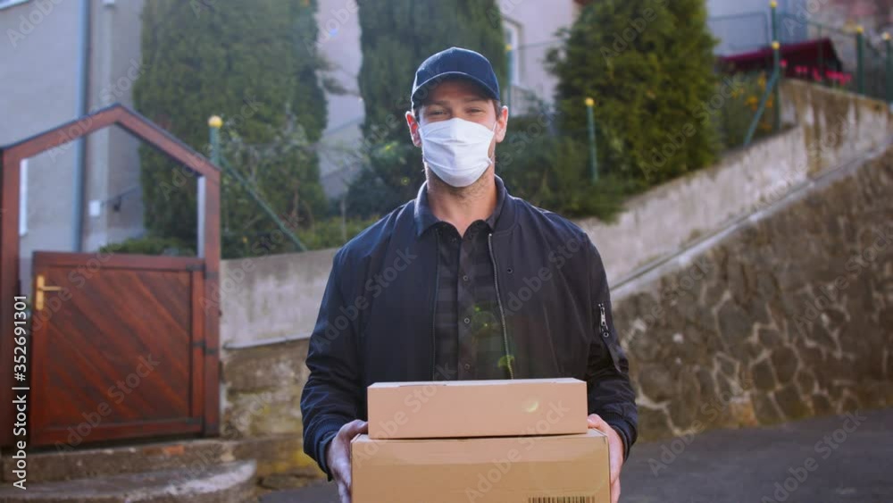 Delivery man courier with face mask delivering parcel boxes in town.