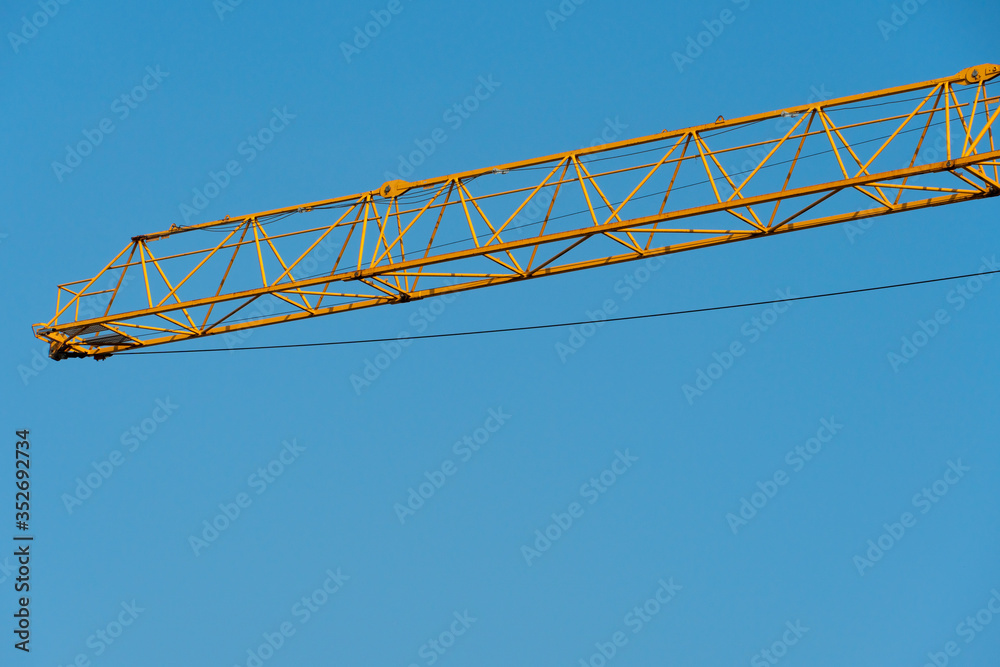 Orange tower crane against a clear blue sky. Construction of a new brick building. Modern construction site. Housing on credit, mortgages, sale of real estate.