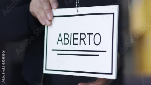 Propietaria de una pequeña empresa gira el cartel para la reapertura del lugar después de la cuarentena debido a covid-19. En México photo