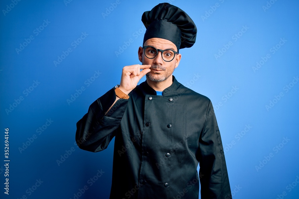 Young handsome chef man wearing cooker uniform and hat over isolated blue background mouth and lips shut as zip with fingers. Secret and silent, taboo talking Young handsome chef man wearing cooker uniform and hat over isolated blue background mouth and lips shut as zip with fingers. Secret and silent, taboo talking