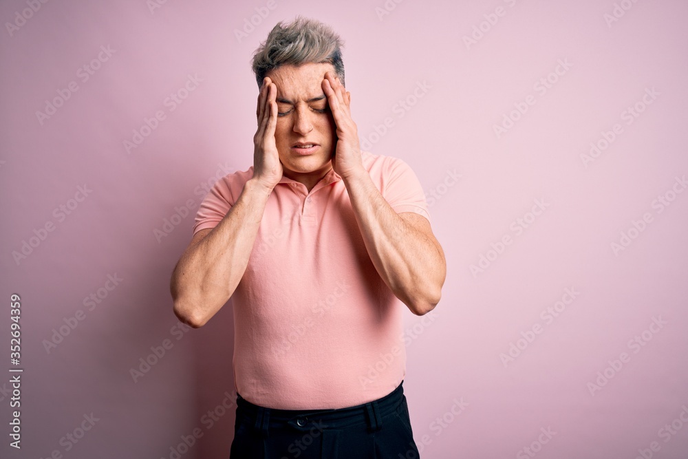 Young handsome modern man wearing casual pink t-shirt over isolated background with hand on head for pain in head because stress. Suffering migraine. Young handsome modern man wearing casual pink t-shirt over isolated background with hand on head for pain in head because stress. Suffering migraine.