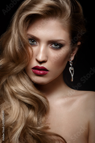 Fototapeta Naklejka Na Ścianę i Meble -  Beautiful girl with red lips and classic makeup and curls. Beauty face