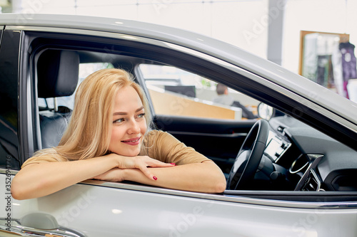 I wish I had such a car! woman dream, want to buy a car, she sits inside of auto, like it, female look side. in dealership