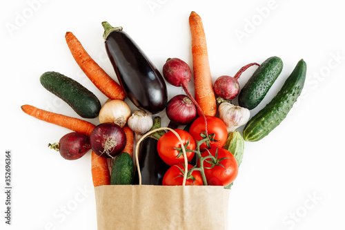Fresh regional vegetables and fruits in a paper bag on a white table isolated. Flat lay, healthy eating. Zero waste concept